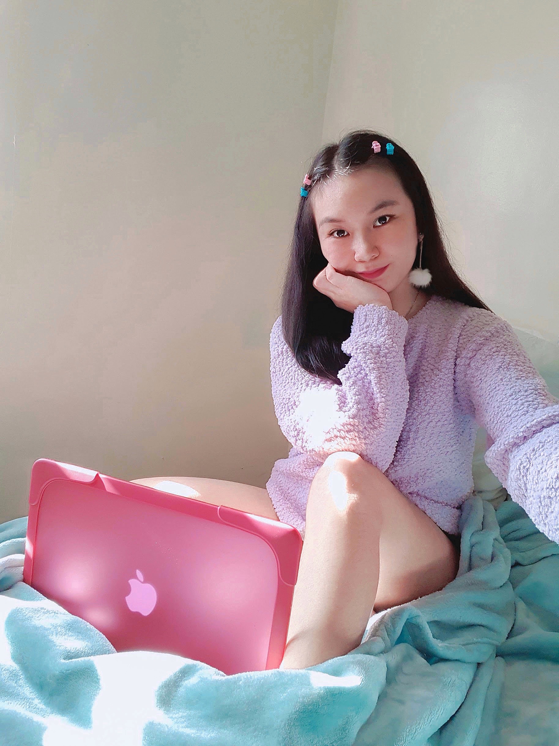 Roxanne Lacap at bed with a pink laptop