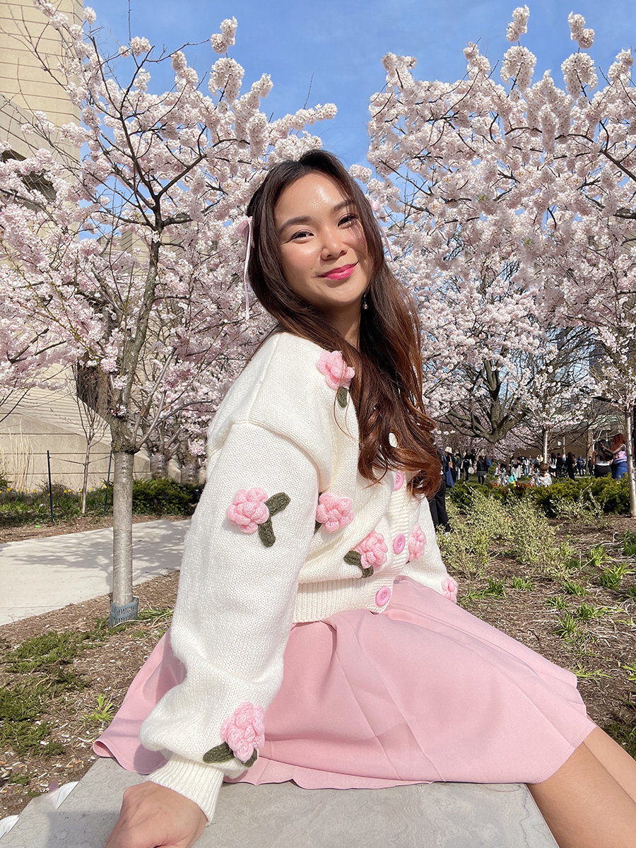 A cute lady poses in front of beautiful pink cherry blossoms scenery at Roberts Library in Toronto Canada