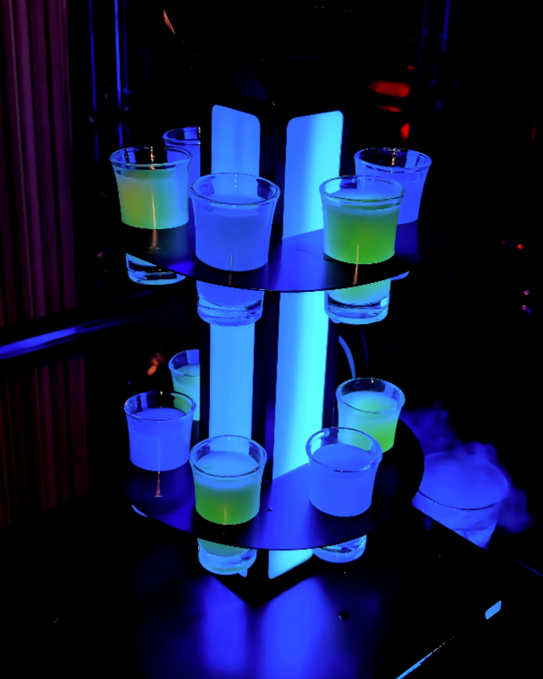 A close up shot of a the multi tiered glowing neon blue and green birthday complimentary shots tower at ET KTV in Markham Toronto Karaoke