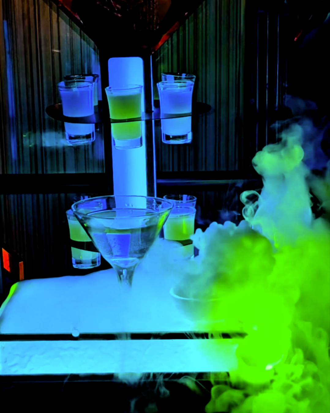 A neon lit birthday freebie drink tower with glowing green and blue shots and dry ice smoke inside a private karaoke lounge at ET KTV Markham Toronto Karaoke.