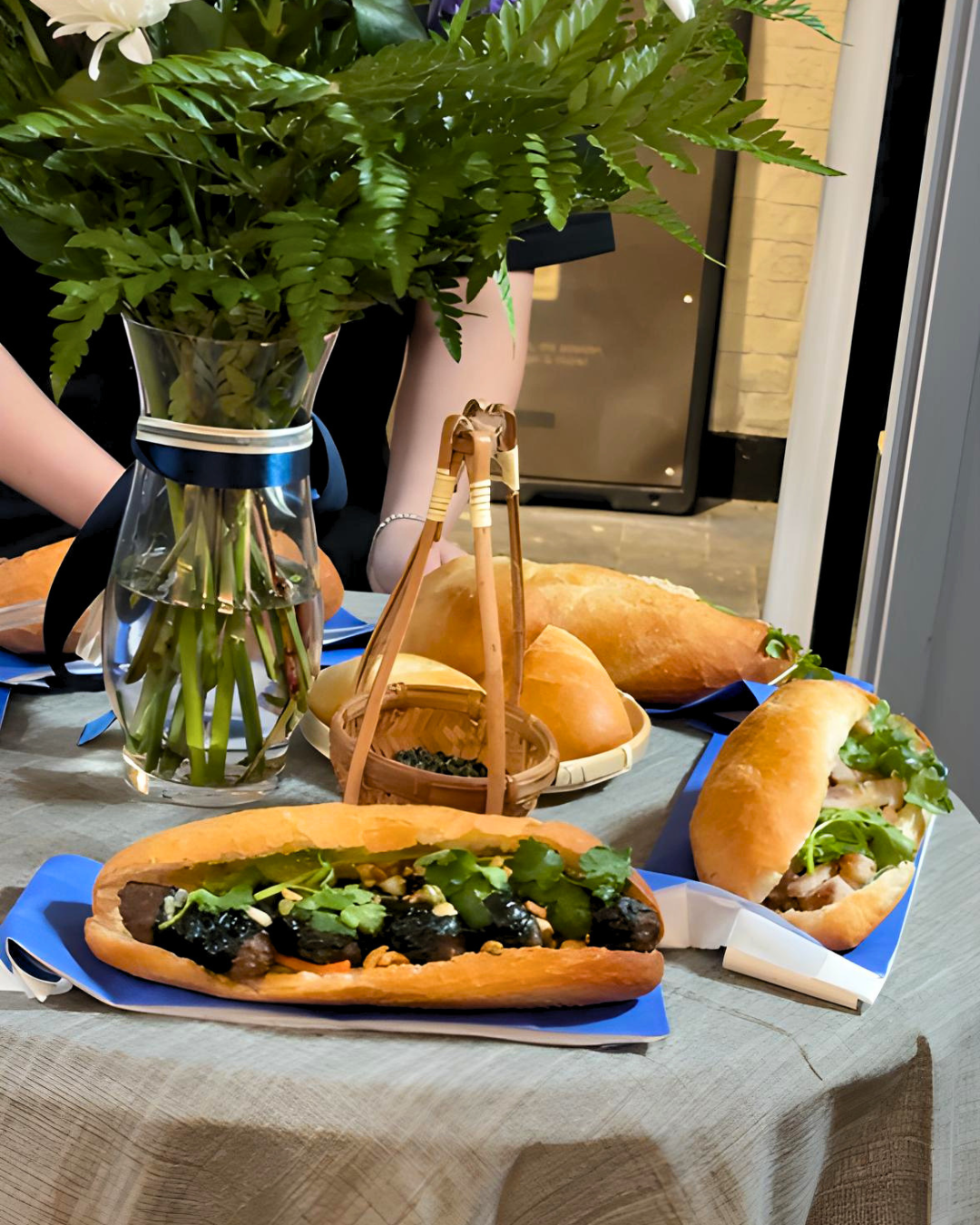 An assortment of fresh banh mi sandwiches displayed on a table setup inside the AndBanhMi shop in Toronto.