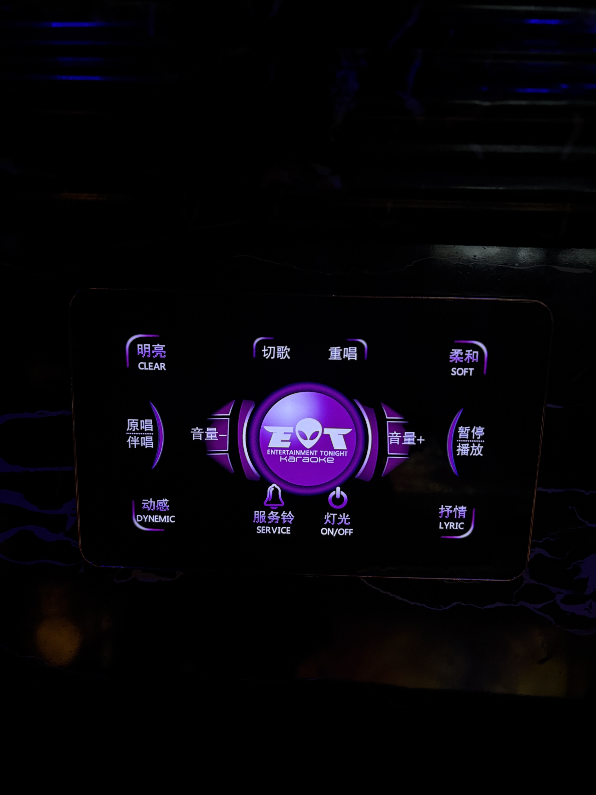 A close up view of a glowing purple digital touch screen control panel mounted to the wall inside a private suite at Entertainment Tonight Karaoke ET KTV Markham.